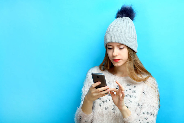 Kış giysileri bir kızı bir akıllı telefon elinde tutuyor. - Fotoğraf, Görsel