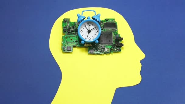 Placa de circuito electrónico y pequeño reloj de campana de alarma, colocado en el contorno amarillo de una cabeza humana masculina, material conceptual
 - Metraje, vídeo