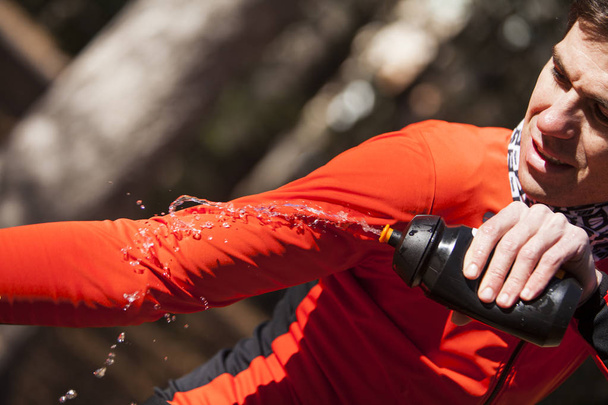 cyklista dunking červené sako s kastrolkem vody - Fotografie, Obrázek