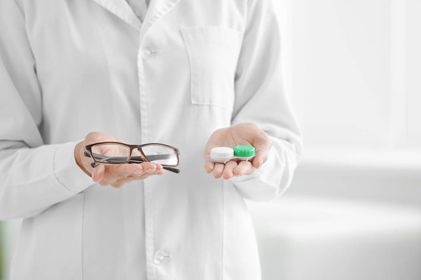 Female doctor holding contact lens case and glasses, closeup - Photo, image