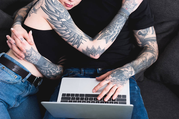 imagen recortada de pareja tatuada utilizando el ordenador portátil
 - Foto, Imagen