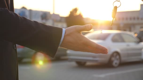 Mužské ruce dává klíče od auta svému příteli se sluneční erupcí na pozadí. Paže obchodníka předala klíč od auta. Potřesení rukou mezi dvěma obchodníky venku. Zavřít Zpomalený pohyb - Záběry, video