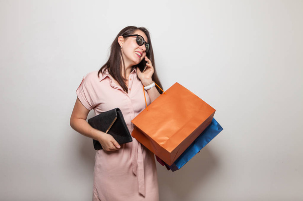 Hermosa mujer moderna con bolso y bolsas de compras llamando a un teléfono
 - Foto, Imagen