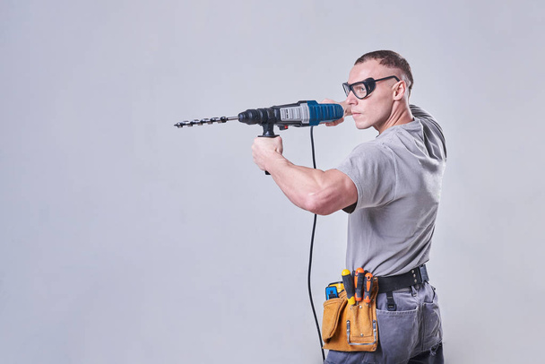 Master Builder-finisher in abiti da lavoro, con un perforatore in mano - Foto, immagini
