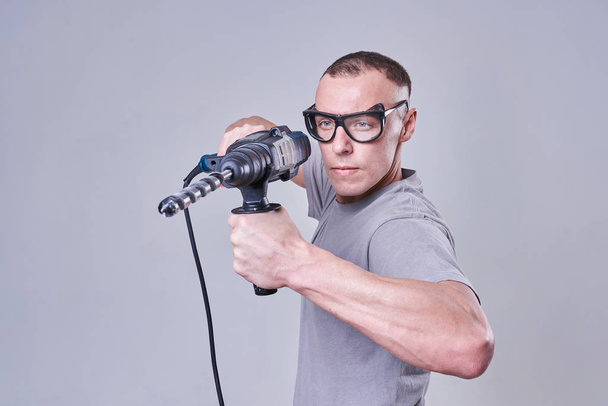 Maître Constructeur-finisseur en vêtements de travail, avec une perforatrice dans les mains - Photo, image