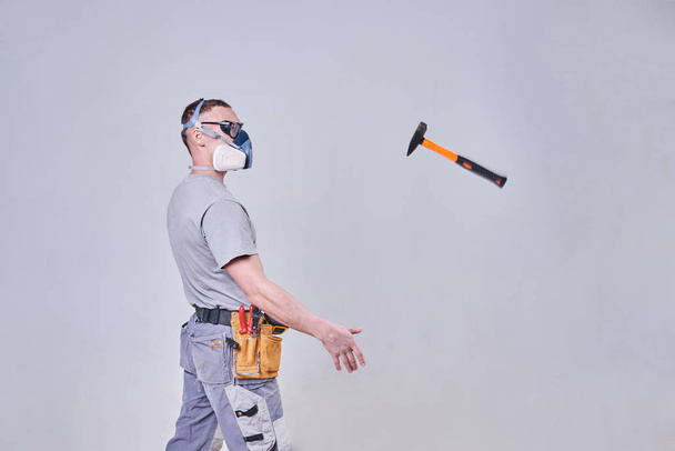 Master Builder-finisher in abiti da lavoro, lancia un martello
 - Foto, immagini