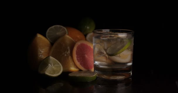 Limette im Glas mit Sodawasser, Zitrusfrüchten, schwarzem Hintergrund. - Filmmaterial, Video