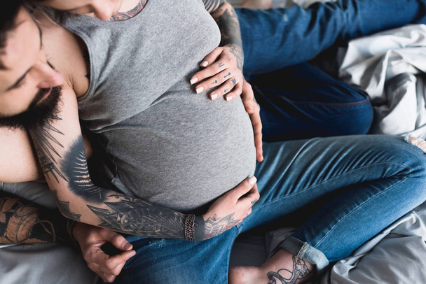 imagen recortada de novio abrazando embarazada tatuado novia en casa
 - Foto, imagen