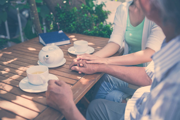 Immagine ritagliata di padre e figlia che bevono tè e parlano in un caffè all'aperto
 - Foto, immagini