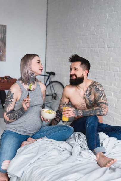 pregnant tattooed girlfriend eating salad at home - Foto, afbeelding