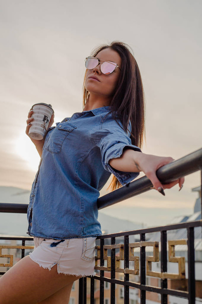 mujer joven sosteniendo taza de café en balcón
  - Foto, imagen