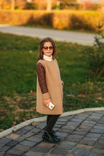 Menina em casaco de outono usando telefone. Outono dourado
 - Foto, Imagem