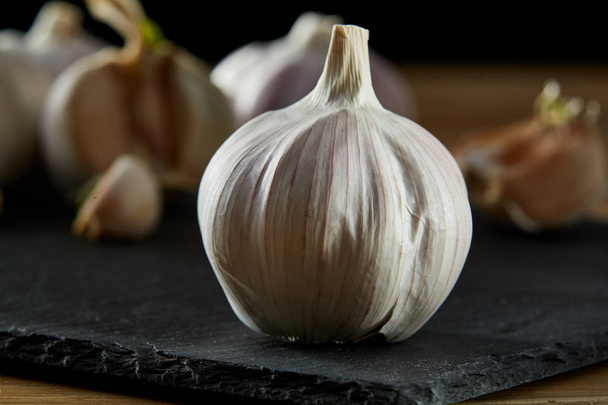 Garlic close up on wooden plate on rustic background, shallow depth of field, selective focus, macro - Foto, immagini
