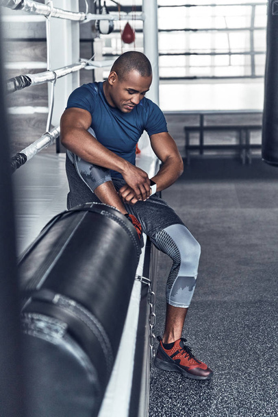 Handsome young African man in sport clothing having break in gym - Фото, изображение
