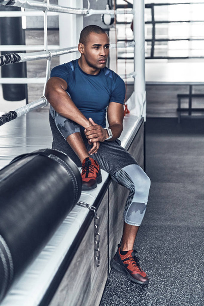 young African man in sport clothing having break in gym - Photo, Image