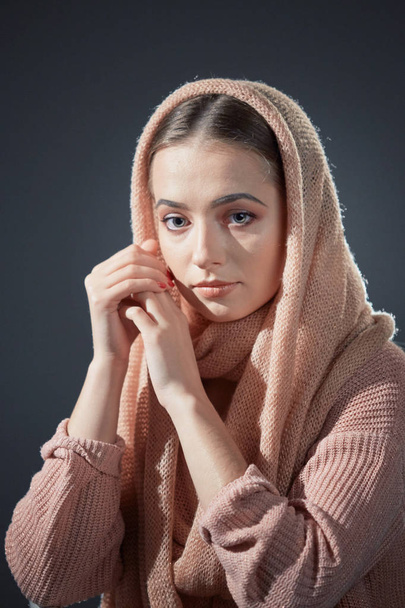 large emotional portrait of a beautiful girl in a knitted pink headscarf in the studio on a gray background. - Foto, Bild