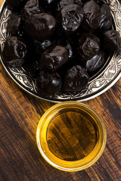 Nahaufnahme von schwarzen Oliven und Olivenöl - Foto, Bild
