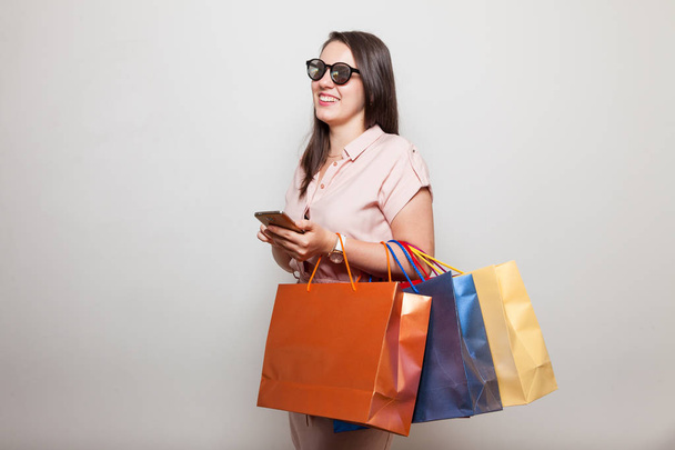 Estudante adolescente elegante com óculos de sol e telefone inteligente faz compras
 - Foto, Imagem
