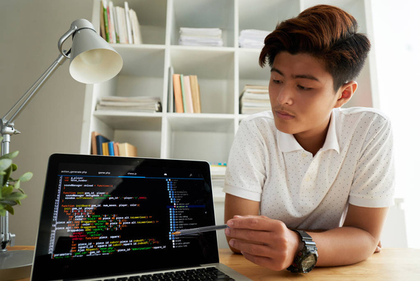 Young Vietnamese programmer explaining code on laptop screen - Photo, Image