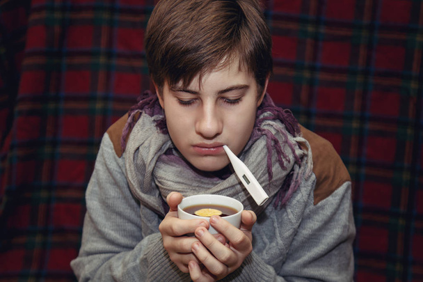  Kranker Teenager mit Thermometer zu Hause. - Foto, Bild