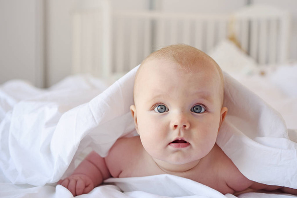 Bebê bonito jaz em uma cama
 - Foto, Imagem