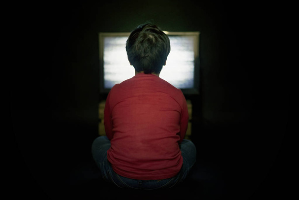 chłopiec oglądania telewizji na czarnym tle - Zdjęcie, obraz