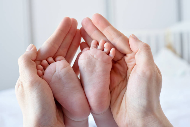 Padres sosteniendo en las manos los pies del bebé
 - Foto, imagen