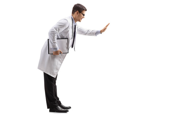 Full length profile shot of a doctor with a clipboard making a high-five gesture isolated on white background - Photo, image