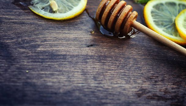 Honey and lemon. Honey stick and slices of sliced lemon on a woo - Photo, Image