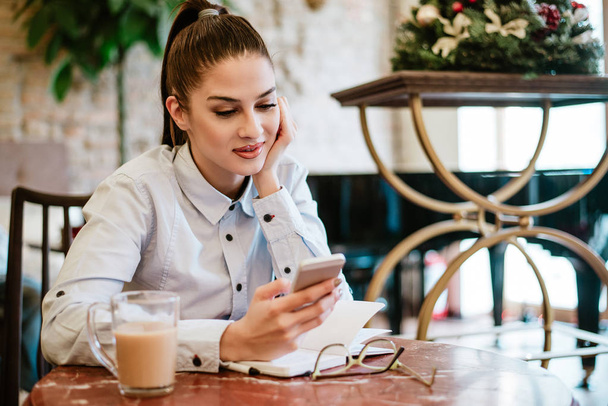 femme utilisant un smartphone tout en étant assis dans un café
 - Photo, image