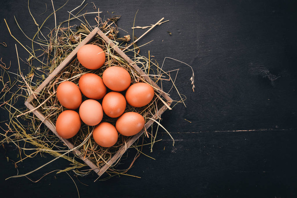 Chicken raw eggs in a wooden basket. On a wooden background. Top view. Copy space. - Foto, Bild