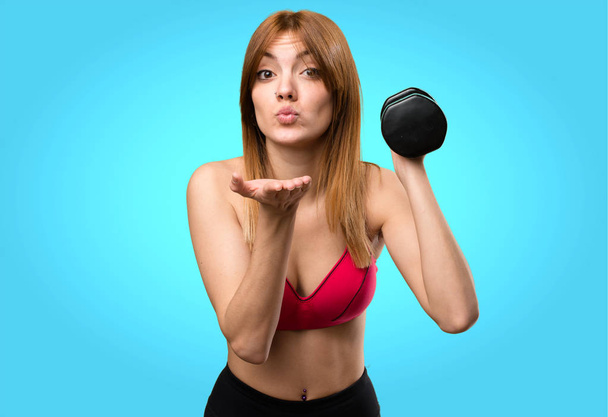 Beautiful sport woman with dumbbells sending a kiss on colorful  - Foto, imagen