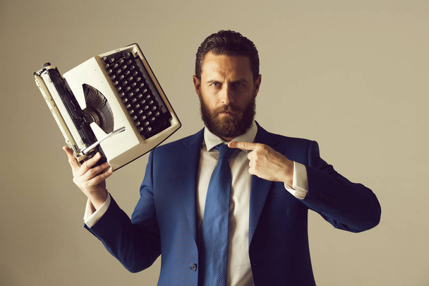 liikemies sininen puku ja solmio kirjoituskoneen kanssa
 - Valokuva, kuva