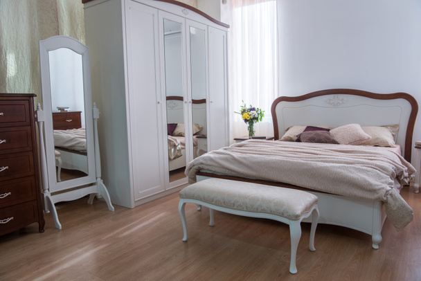 Interior del acogedor dormitorio con armario, cama y espejos en diseño moderno
 - Foto, imagen