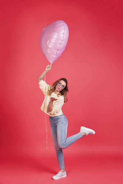 Full length of attractive young woman holding balloon and blowing a kiss in studio - Fotoğraf, Görsel