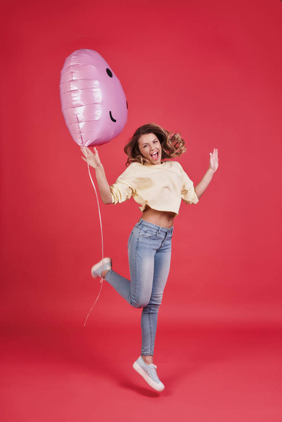 happy woman holding heart shaped balloon and shouting against pink background - Foto, immagini