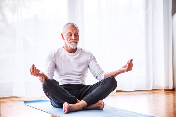 Senior man meditating at home. - Φωτογραφία, εικόνα