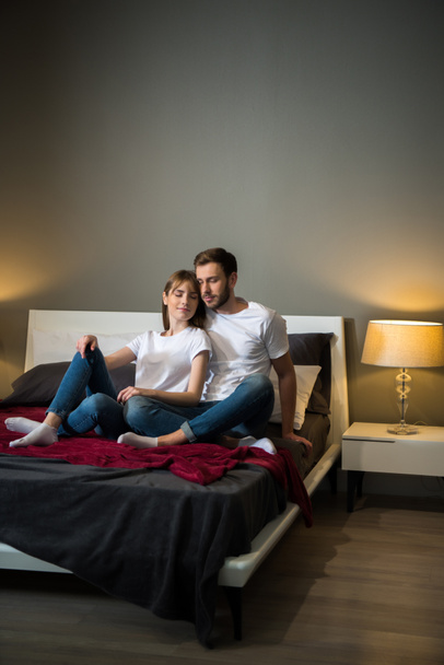 Couple assis avec les yeux fermés dans la chambre à coucher avec intérieur moderne
 - Photo, image