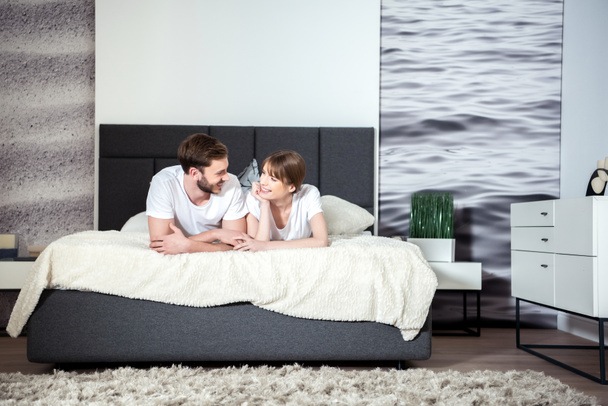 Onnellinen pari makaa ja puhuu viihtyisä moderni makuuhuone
 - Valokuva, kuva