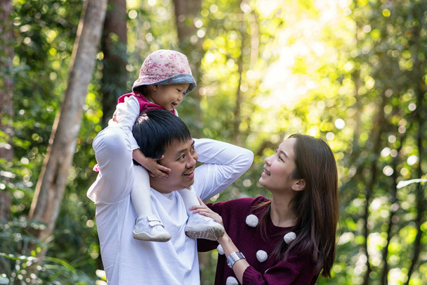 Mãe asiática com o pai estava montando pescoço por filha na floresta profunda, conceito de família e amor
 - Foto, Imagem