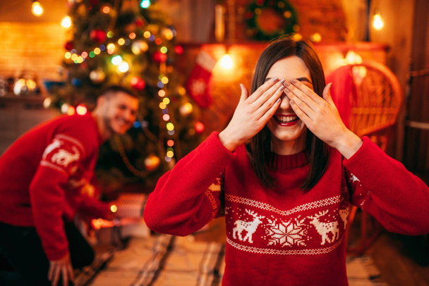 Celebración de Navidad, marido haciendo sorpresa a la esposa, abeto con decoración en el fondo
 - Foto, Imagen