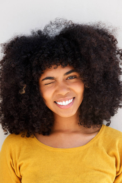 かなり若い黒人女性の目をウインクと笑顔の肖像画を間近します。 - 写真・画像