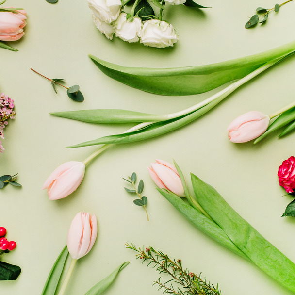 Modèle de fleurs faites de tulipes roses, roses, fleur d'hypericum sur fond vert. Pose plate, vue du dessus printemps concept floral
. - Photo, image