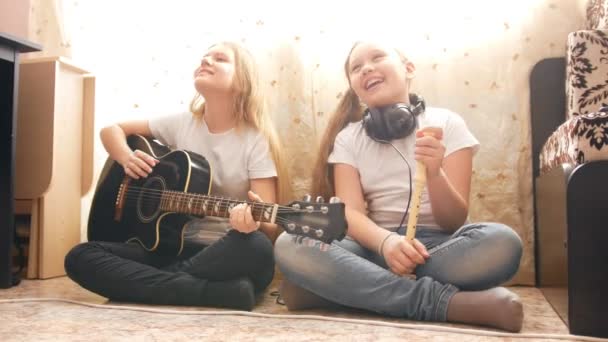 Two female teens playing musical instruments at home - Footage, Video