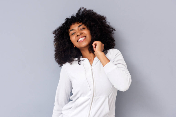 Porträt eines fröhlichen jungen schwarzen Mädchens, das vor grauer Wand steht - Foto, Bild