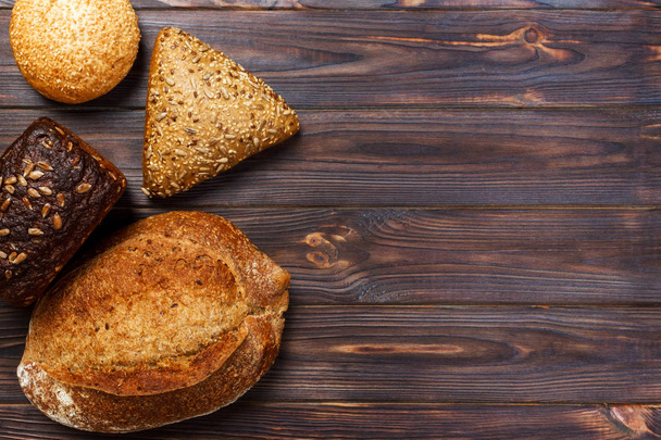 Assortment of baked bread on wooden table background. top view with copy space - Фото, зображення