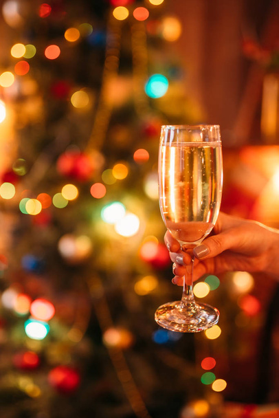 Mão feminina segurando vidro com champanhe, tradição de Natal, celebração romântica
 - Foto, Imagem