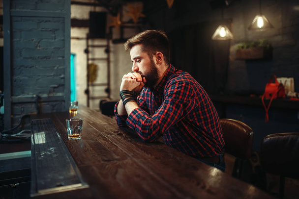 young man with glass of whiskey at bar counter, alcoholism,  drunkenness concept - Фото, зображення