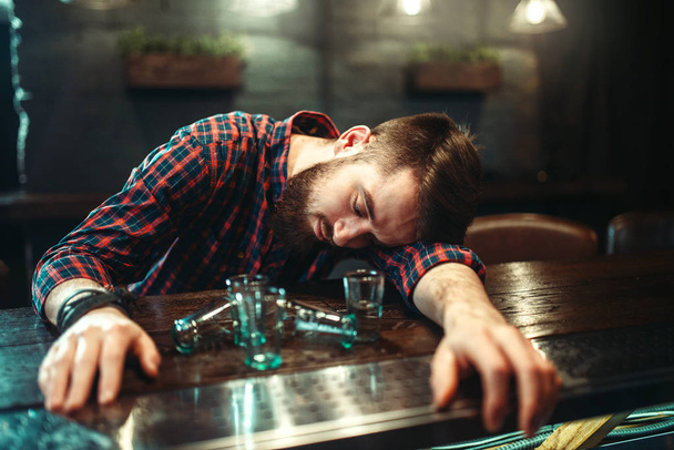 joven durmiendo en el mostrador del bar después de beber vodka, alcoholismo, concepto de embriaguez
 - Foto, Imagen