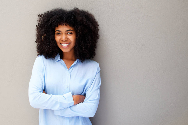 Ritratto di giovane donna afroamericana felice sorridente su sfondo grigio con le braccia incrociate
 - Foto, immagini